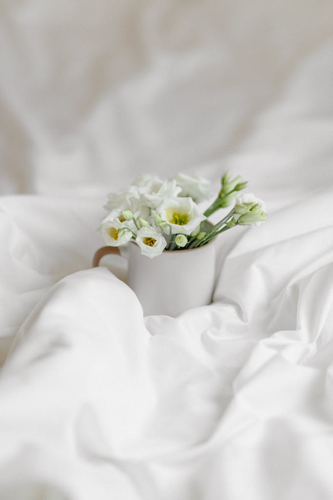 Aesthetic white flowers in a mug on a soft linen backdrop, conveying serenity and elegance.